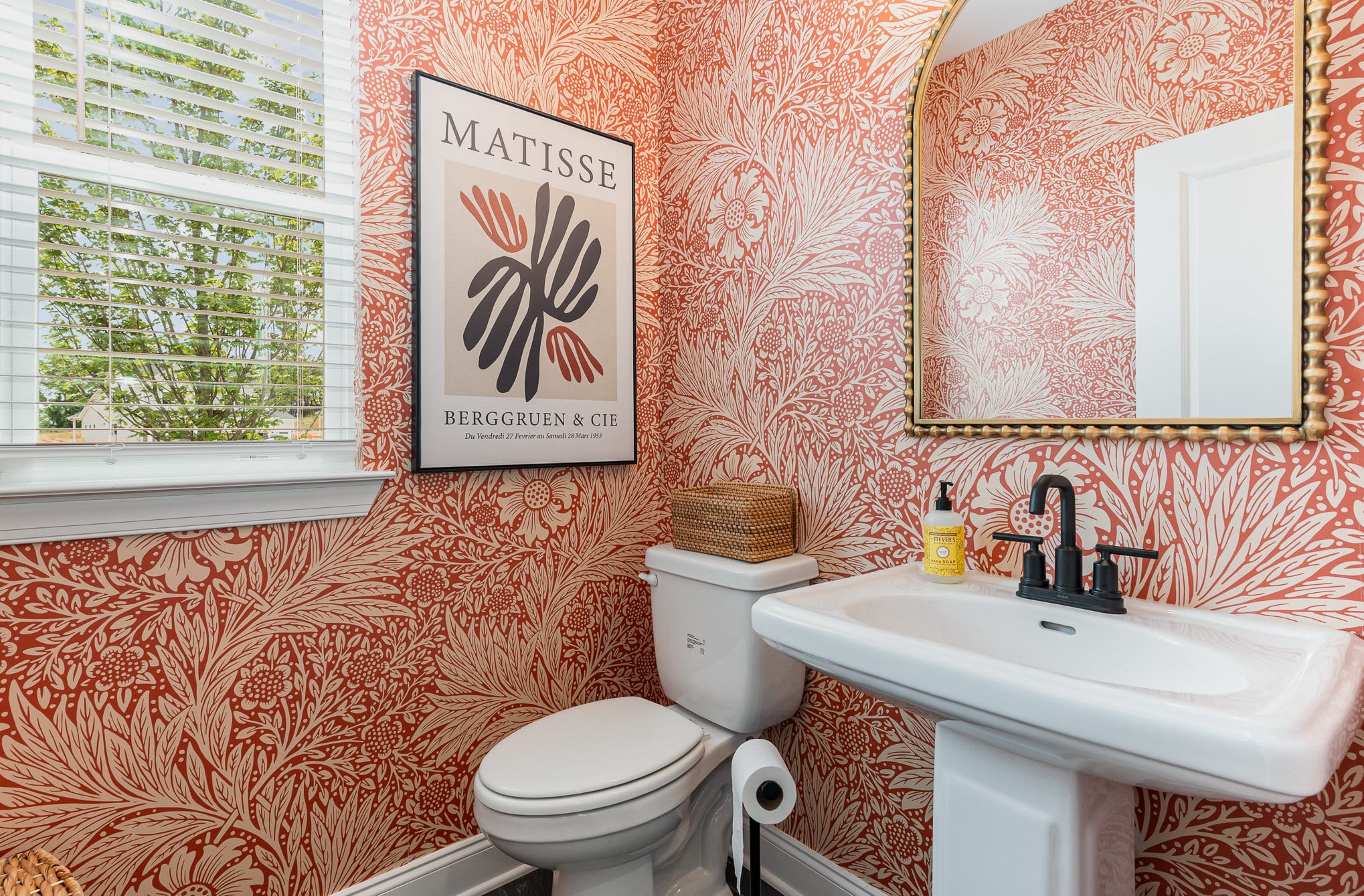 A bathroom with floral wallpaper in a Harpeth series home by Patterson Company