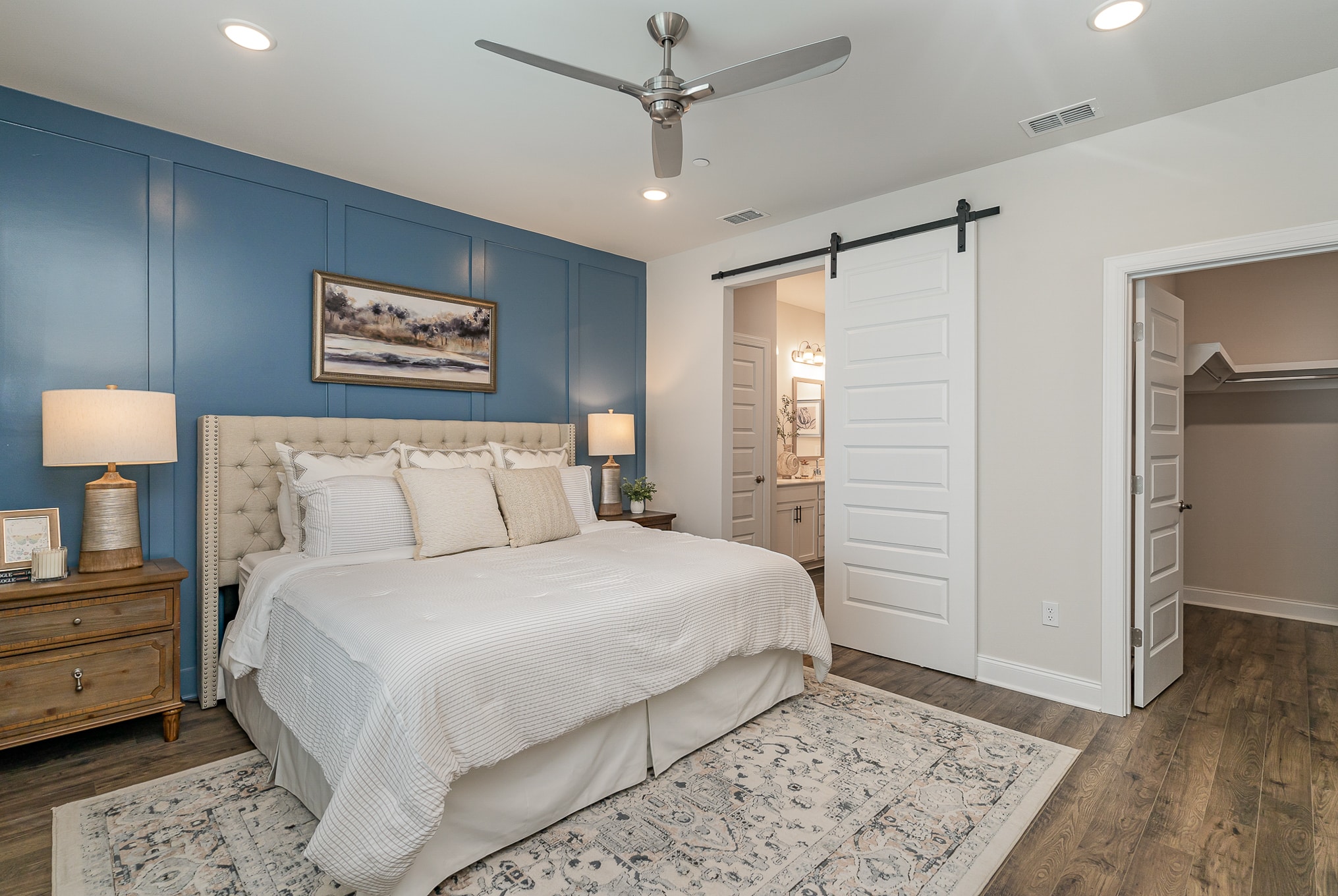A bedroom with a blue accent wall in the Hanover series model home by Patterson Company